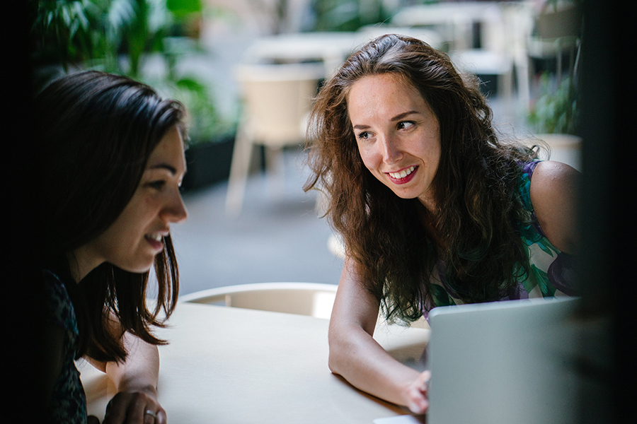 Dos mujeres hablan mientras miran la pantalla de una computadora.