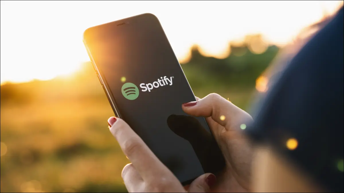 شخص يستخدم هاتفًا ذكيًا عليه شعار Spotify
