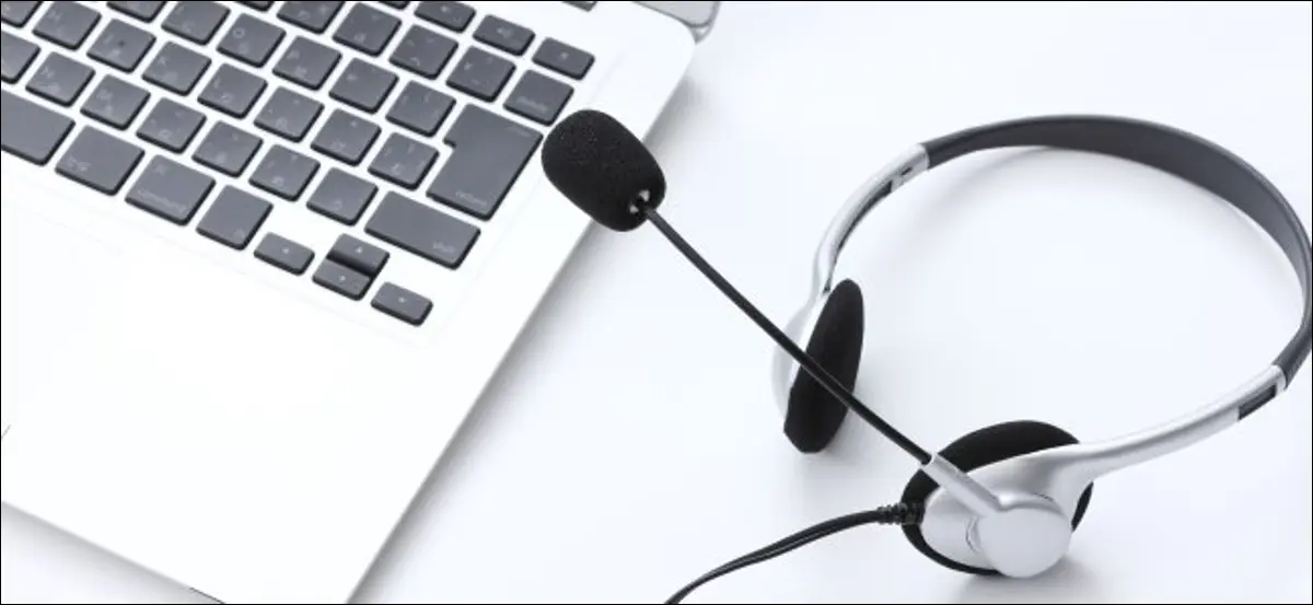 Um fone de ouvido com microfone ao lado de um teclado MacBook.