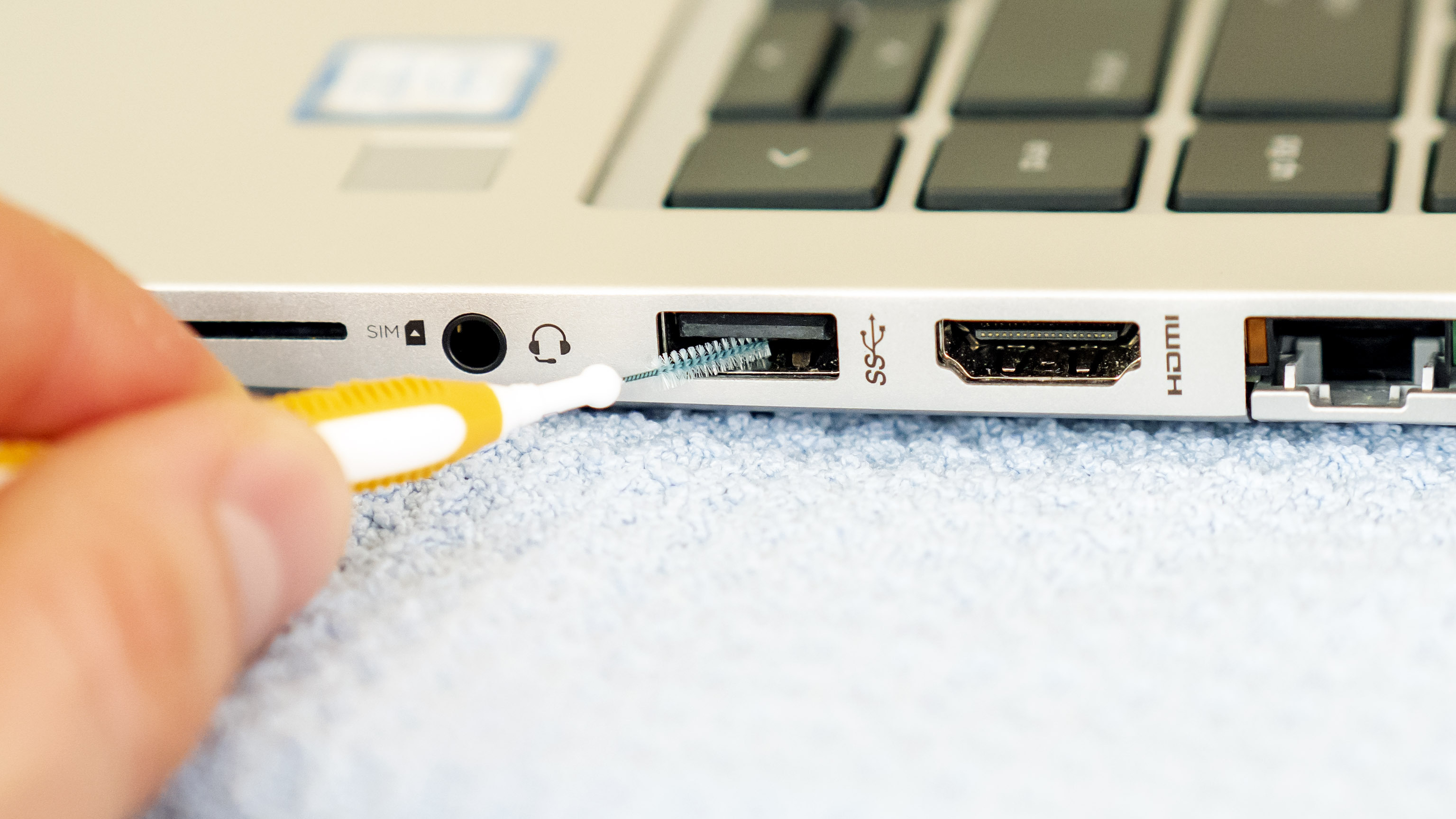 Czyszczenie portów laptopa za pomocą małej wysuwanej szczoteczki
