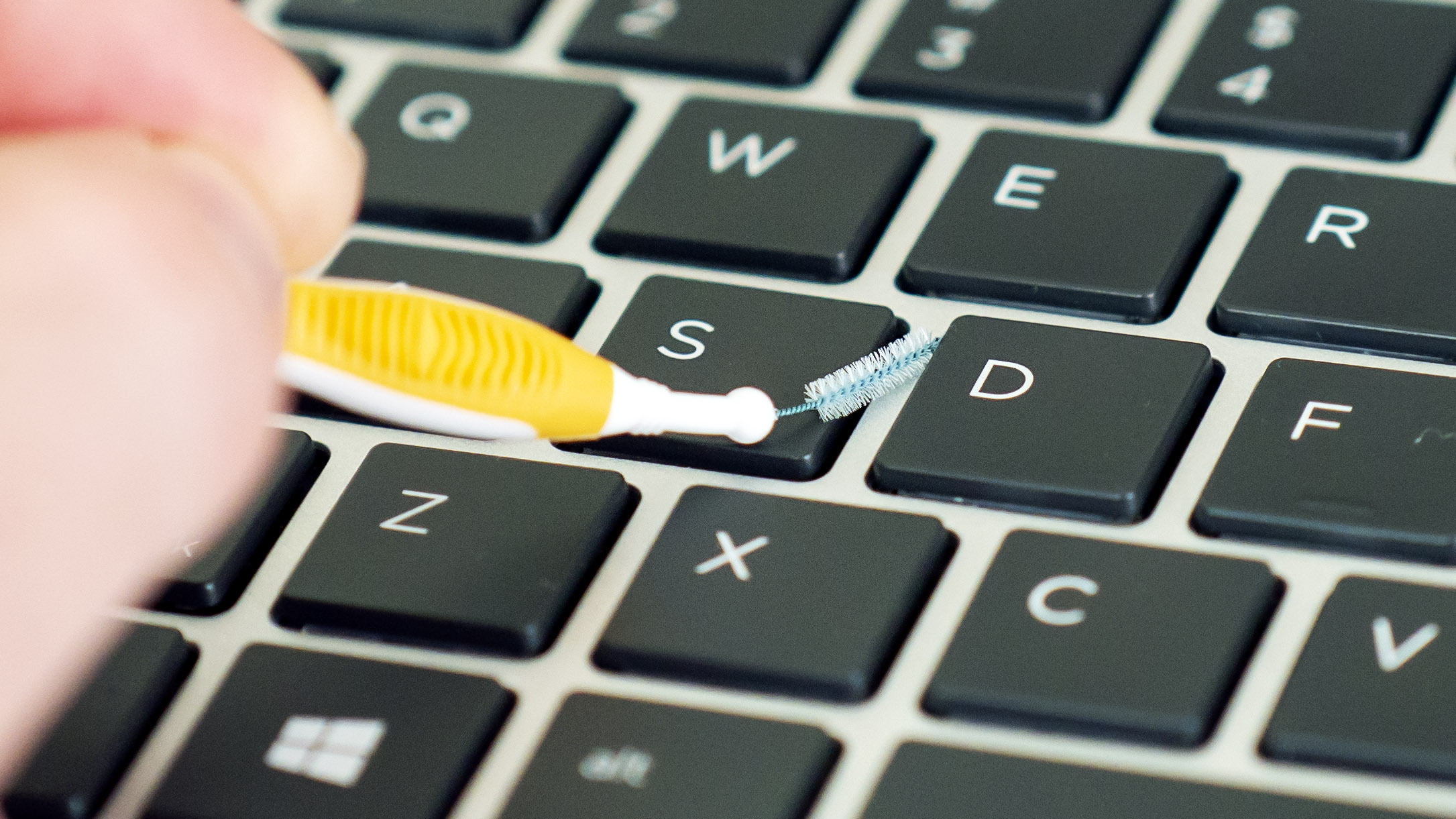 Czyszczenie klawiatury laptopa za pomocą małej wysuwanej szczoteczki