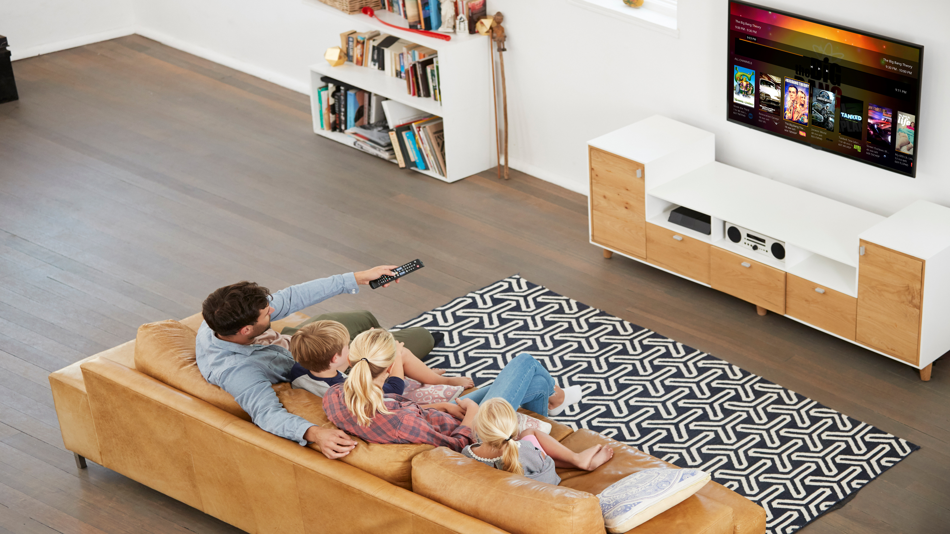 أسرة جالسة على أريكة تتنقل عبر واجهة plex على التلفزيون