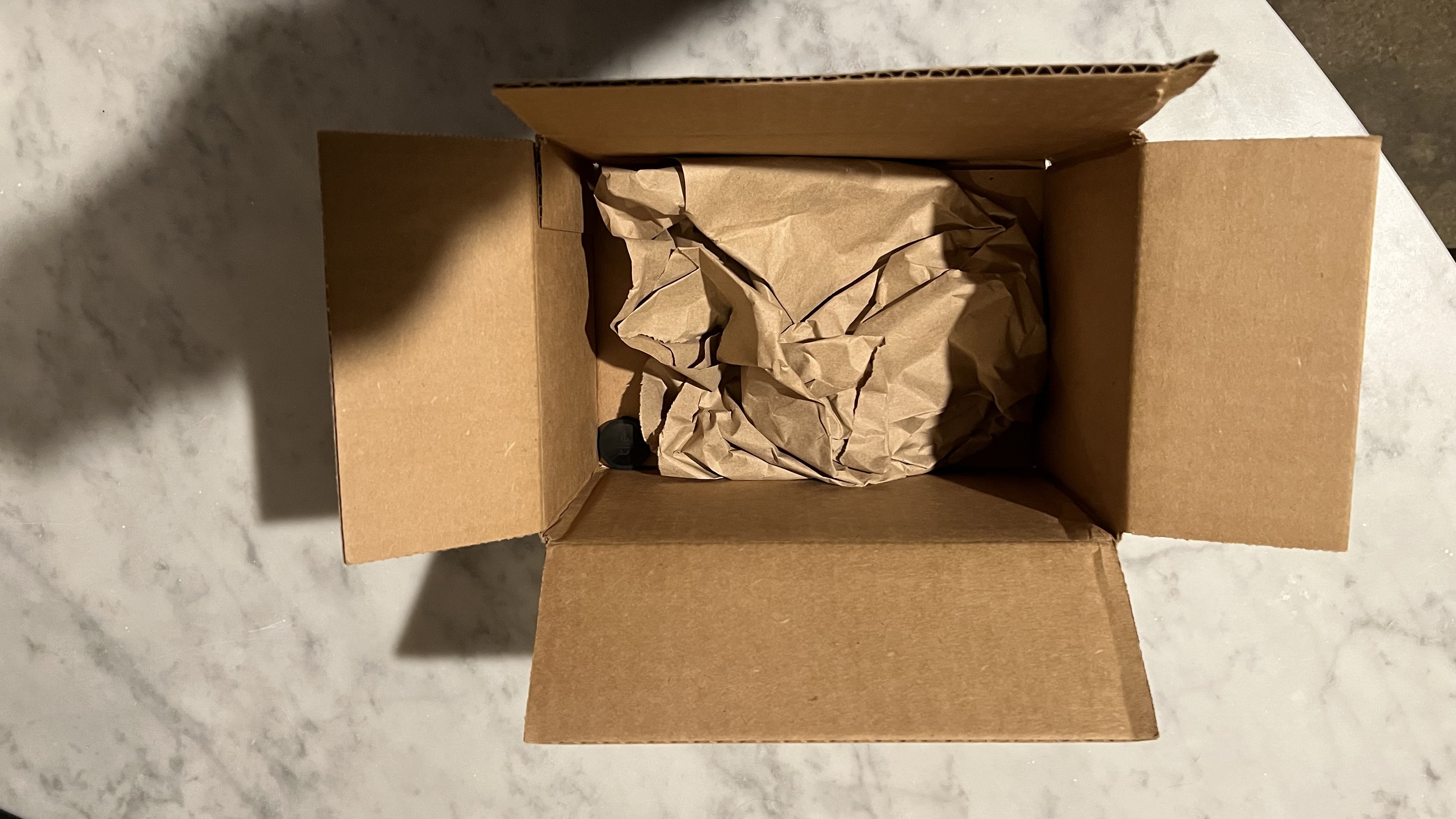 Box mit einem unter Verpackungsmaterial versteckten Bluetooth-Tracker.