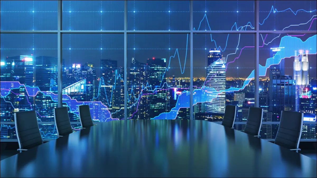 O masă de conferință cu un grafic forex și o vedere a unui oraș pe timp de noapte în fereastră.