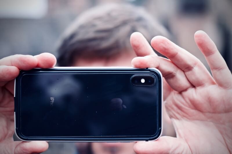 Mężczyzna trzymający iPhone'a poziomo
