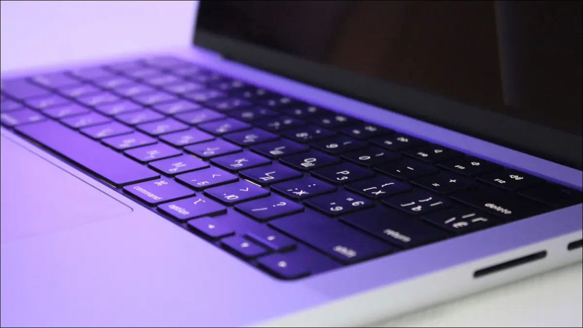 صورة مقربة لجهاز MacBook Pro M1 تحت إضاءة أرجوانية.