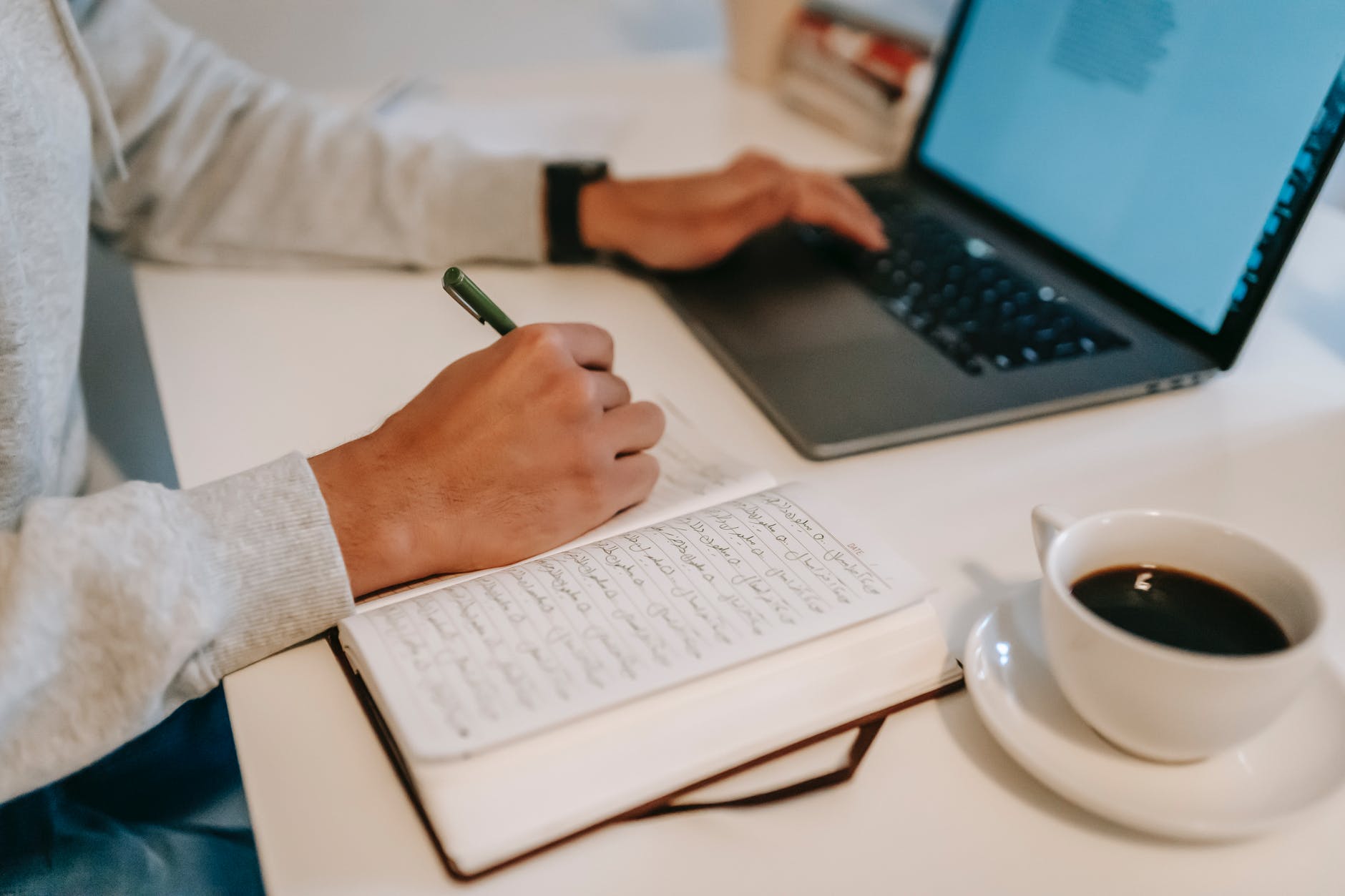 freelance navegando por la computadora portátil y tomando notas en el cuaderno durante el trabajo