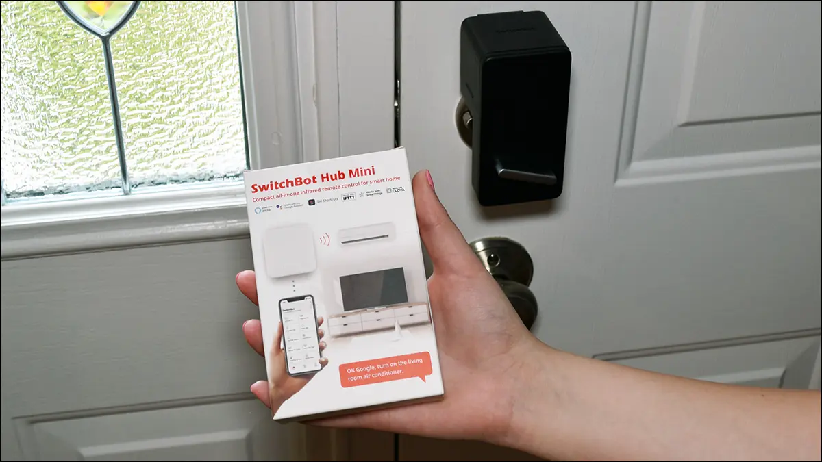 Mâna ținând cutia SwitchBot Hub Mini.