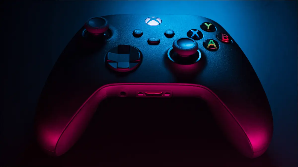 Tampilan dekat pengontrol Xbox Series S karbon hitam dalam pencahayaan biru dan merah.