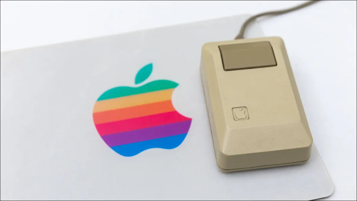 Une souris d'ordinateur Apple vintage sur un tapis de souris avec le logo Apple arc-en-ciel.