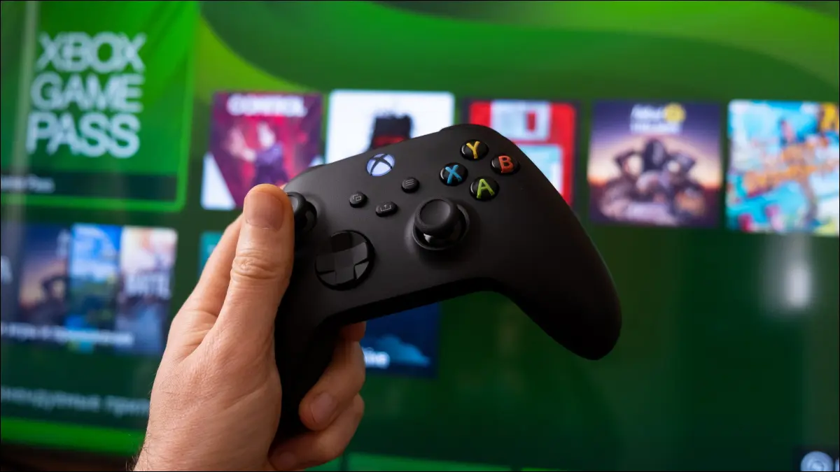 Una mano che tiene un controller Xbox Series X davanti a Game Pass sulla console.