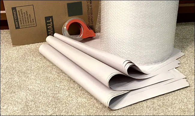 Os materiais de embalagem necessários: uma caixa de papelão, papel de jornal, plástico bolha e fita adesiva.