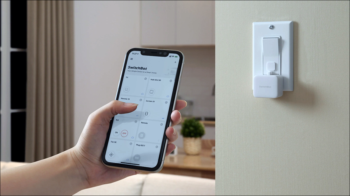 Teléfono inteligente de mano con la aplicación SwitchBot en primer plano y SwitchBot Bot en segundo plano