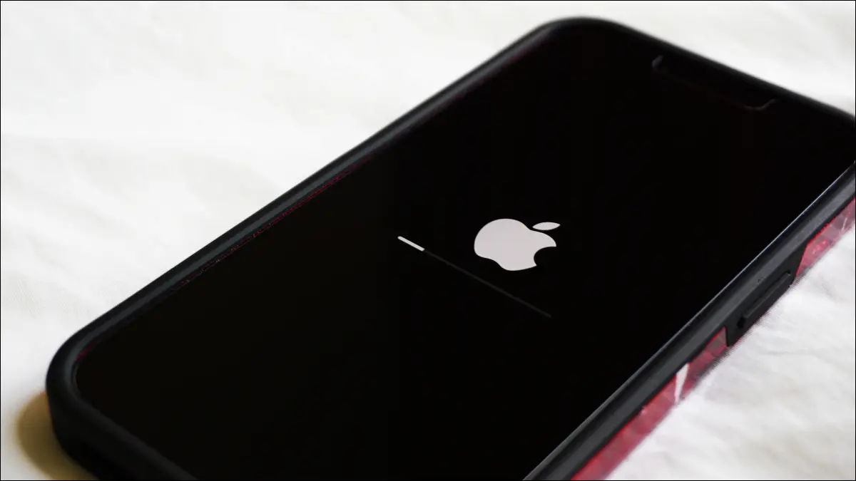 Apple ロゴとソフトウェア アップグレードの進行状況バーが画面に表示されている、白い卓上の iPhone の拡大図。