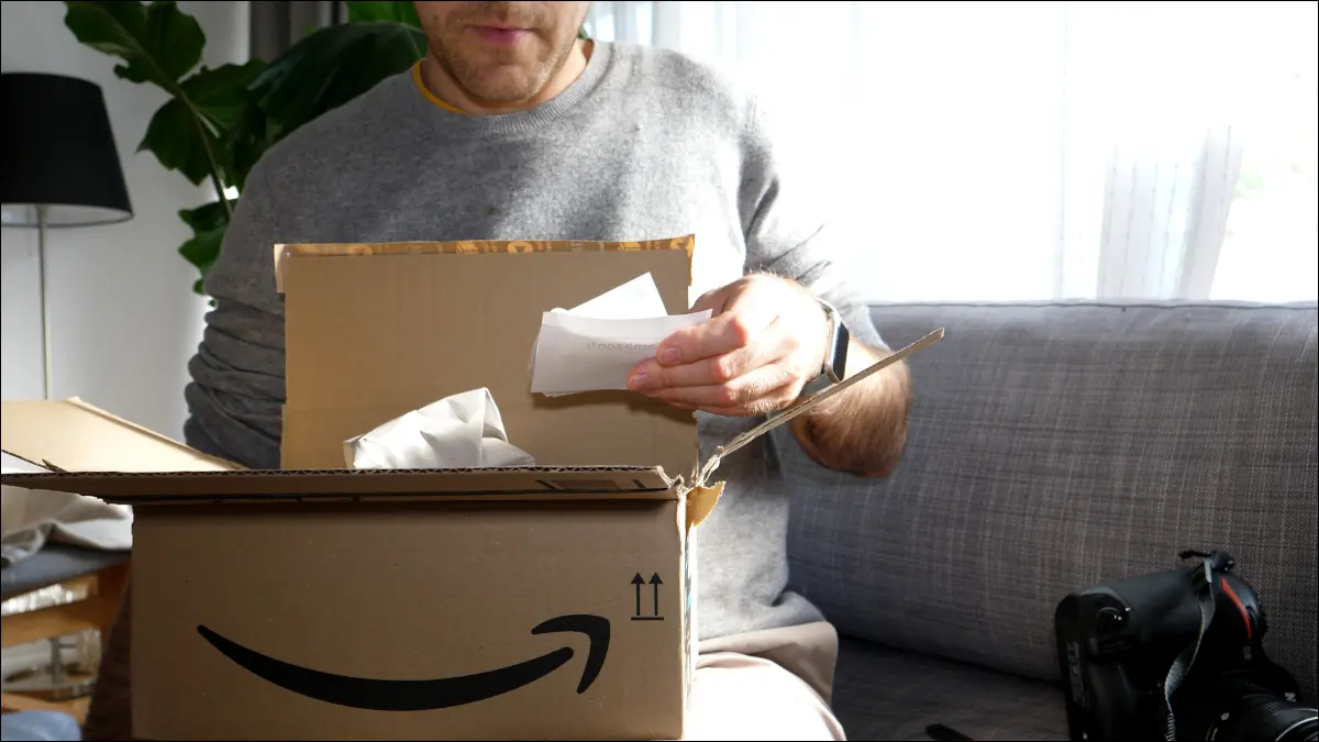 Mann öffnet ein Amazon-Paket und liest den Bestellschein.