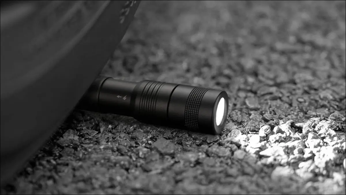 坚固的 Anker 笔式手电筒放在轮胎下的路上。