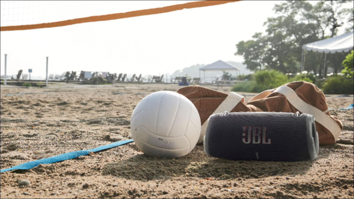 Enceinte Bluetooth portable JBL XTREME3 posée sur le sable sous un filet de volley-ball
