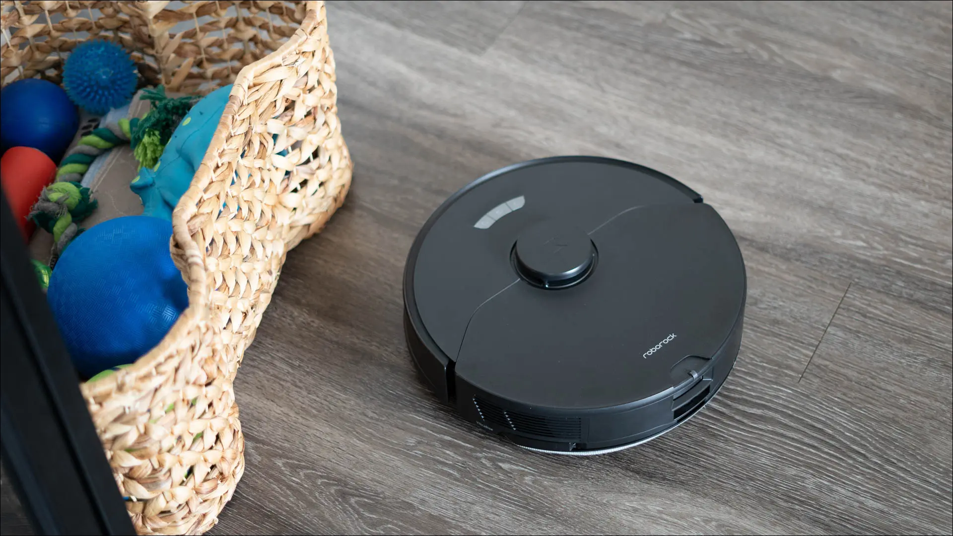 Der Roborock S7 Max Ultra saugt in der Nähe eines Behälters mit Hundespielzeug